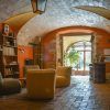 Una acogedora sala que evoca el encanto de una masía catalana del siglo XVIII, con techo abovedado, cómodos sillones y estanterías. La entrada, soleada y llena de plantas, da una cálida bienvenida, como la Escapada de quesos de Mas Alba. - ForTwo - Planes para parejas