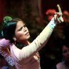 Una bailaora de flamenco cautiva al público borroso bajo las luces del escenario de Sevilla, que recuerdan a una "Escapada con bañera de hidromasaje, cava y crucero por el Guadalquivir", con el brazo levantado con pasión. - ForTwo - Planes para parejas