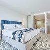 Disfrute de la elegancia moderna en el Hotel Eurostars Ibiza, donde le esperan una cama espaciosa, detalles azules, azulejos geométricos y un baño abierto con bañera y ducha. - ForTwo - Planes para parejas