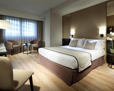 Alójese en el Hotel Eurostars Rey Don Jaime en Valencia y disfrute de una habitación contemporánea con una cómoda cama doble, elegantes sillones y un moderno escritorio, todo ello complementado con vistas al animado paisaje urbano a través de cortinas transparentes. - ForTwo - Planes para parejas