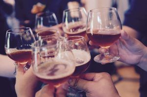 Primer plano de manos tintineando vasos de líquido ámbar durante un vibrante Taller de cata y degustación de cerveza en Barcelona. - ForTwo - Planes para parejas