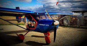 Un avión azul con ruedas rojas y una hélice se encuentra en la pista de Toledo bajo las nubes, listo para su próximo viaje como parte del "Curso de vuelo deportivo por un día (Toledo). - ForTwo - Planes para parejas
