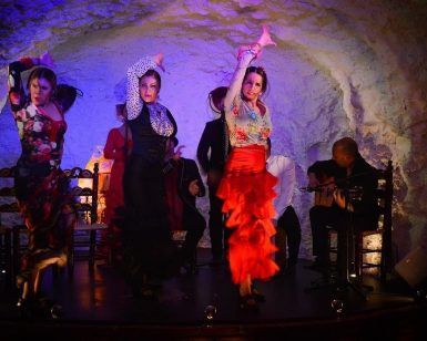 Los bailarines de flamenco actúan enérgicamente en el escenario con guitarristas de fondo, creando un electrizante "El Templo del Flamenco - Cena con espectáculo" en un entorno similar a una cueva. - ForTwo - Planes para parejas