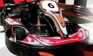 Un kart rojo y negro, con un número 6 en su capó, de la ¡Carrera de Karts en Fórmula Karting Granada!, está estacionado en una pista cubierta en Granada. - ForTwo - Planes para parejas