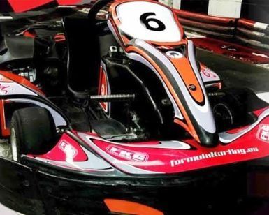 Un kart rojo y negro, con un número 6 en su capó, de la ¡Carrera de Karts en Fórmula Karting Granada!, está estacionado en una pista cubierta en Granada. - ForTwo - Planes para parejas