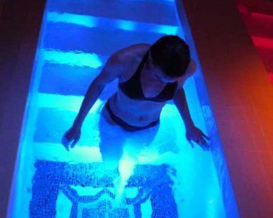 En una pequeña piscina con agua azul brillante, que evoca el ambiente relajante de una estancia en "Habitación doble y circuito de aguas saludables en Balneario de Lanjarón (Granada)", una persona se encuentra elegantemente en traje de baño. - ForTwo - Planes para parejas