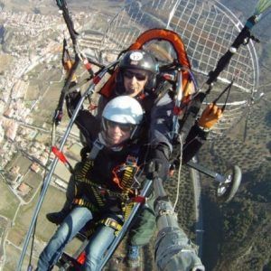 Con un palo de selfie en mano, dos aventureros disfrutan de un emocionante vuelo en paramotor en Granada, capturando impresionantes vistas del paisaje y la ciudad. Volar en parapente sobre Granada crea recuerdos inolvidables con su impresionante telón de fondo. - ForTwo - Planes para parejas