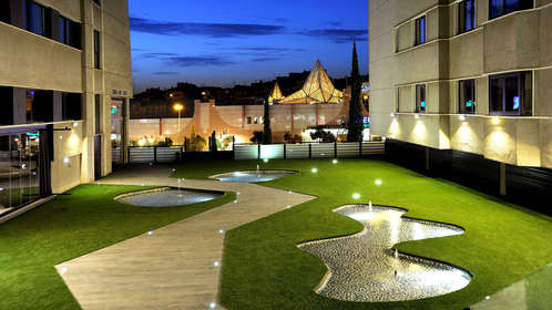 Experimente la tranquilidad en el moderno patio del hotel Sercotel Gran Luna de 4*, con estanques iluminados y senderos serpenteantes. Disfrute de una escapada tranquila con spa y gimnasio. - ForTwo - Planes para parejas
