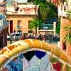 Explora el vibrante banco de mosaico situado entre edificios de piedra y palmeras en el Free Tour por Barcelona en el Park Güell. - ForTwo - Planes para parejas