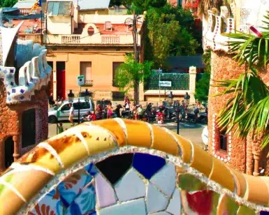 Explora el vibrante banco de mosaico situado entre edificios de piedra y palmeras en el Free Tour por Barcelona en el Park Güell. - ForTwo - Planes para parejas