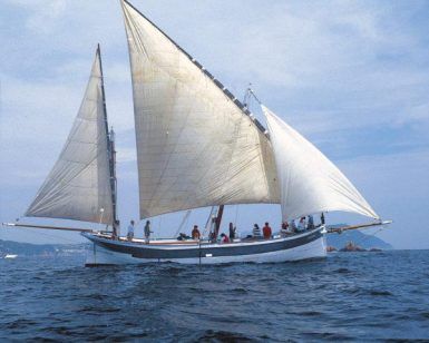 La Garoinada a bordo de un velero de época en Palamós ofrece una pintoresca escena de grandes velas deslizándose en el océano bajo un cielo azul con nubes, capturando el encanto marítimo de la fiesta tradicional. - ForTwo - Planes para parejas