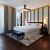 El Gran Hotel Montesol: Curio Collection by Hilton en Ibiza cuenta con una elegante habitación con una cama grande, ventanas de suelo a techo, ventilador de techo y arte enmarcado, que encarna a la perfección la esencia vibrante de Ibiza. - ForTwo - Planes para parejas