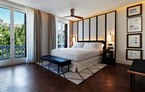 El Gran Hotel Montesol: Curio Collection by Hilton en Ibiza cuenta con una elegante habitación con una cama grande, ventanas de suelo a techo, ventilador de techo y arte enmarcado, que encarna a la perfección la esencia vibrante de Ibiza. - ForTwo - Planes para parejas