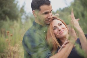 En una hermosa imagen de la "Sesión de fotografía en pareja por Carlos Fierro", una pareja se abraza en un campo de hierba, la mujer levanta alegremente su mano. - ForTwo - Planes para parejas
