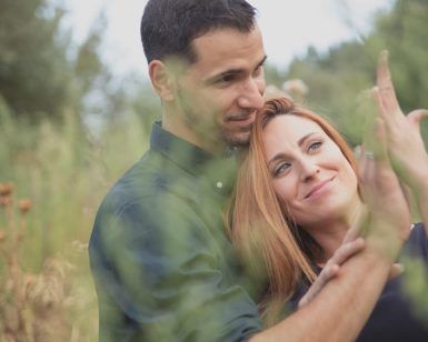 En una hermosa imagen de la "Sesión de fotografía en pareja por Carlos Fierro", una pareja se abraza en un campo de hierba, la mujer levanta alegremente su mano. - ForTwo - Planes para parejas