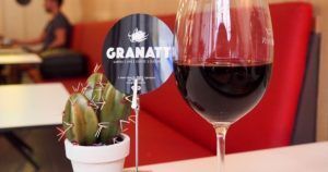 En Granatti en Gràcia, conocido por su "Maridaje de arroz y vino", una copa de vino complementa un pequeño cactus en la mesa, con asientos rojos que se suman al ambiente acogedor. - ForTwo - Planes para parejas