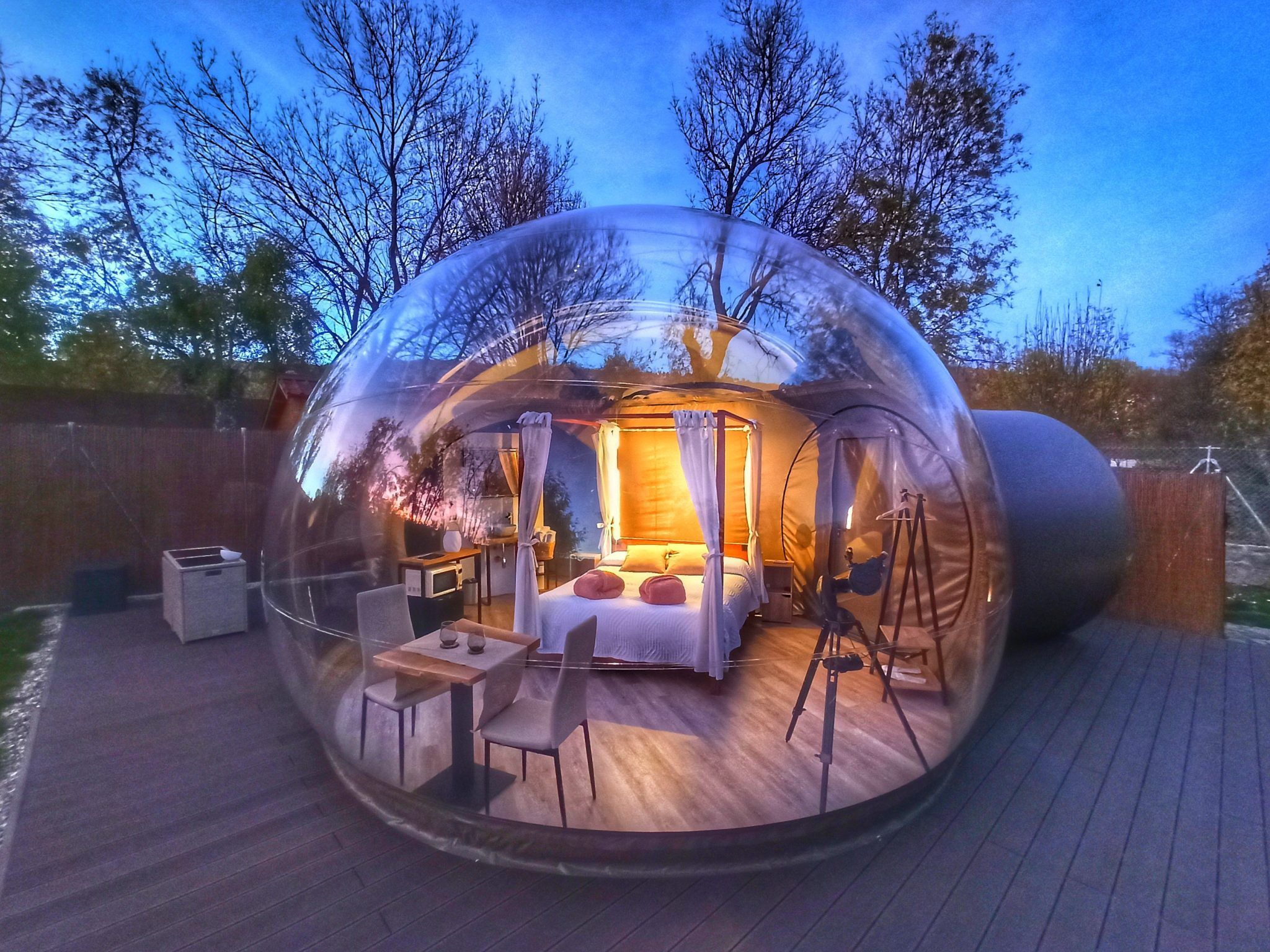 Rodeada de imponentes árboles al atardecer, la cúpula transparente ofrece un dormitorio íntimo ideal para una escapada romántica. Descubre la magia de Gredos Estelar en la "Escapada romántica en hotel burbuja con Gredos Estelar (Ávila)" para una escapada inolvidable. - ForTwo - Planes para parejas
