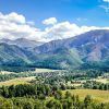 La "Visita guiada a Zakopane y a las Tatras (Cracovia)" muestra un paisaje montañoso con exuberante vegetación, un pintoresco pueblo y un cielo azul salpicado de nubes. - ForTwo - Planes para parejas
