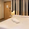 Disfruta de una moderna habitación de hotel en Bilbao con una cama impecablemente hecha, tres toallas enrolladas, un cabecero a rayas y una puerta a la izquierda. Ideal para viajeros que buscan comodidad en el Hostel Bcool Bilbao. - ForTwo - Planes para parejas