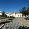 Un camino de piedra conduce a encantadoras casas blancas con chimeneas en Guadix, enclavadas como joyas bajo un cielo azul nítido, capturando la esencia de "Una noche en cueva romántica de turismo rural (Guadix)", donde los árboles escasos se alzan como centinelas. - ForTwo - Planes para parejas