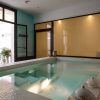La sala de la piscina cubierta cuenta con paredes de azulejos, detalles en verde azulado y amplios ventanales. Las teteras junto a la piscina transmiten una atmósfera acogedora que evoca una tarde tranquila en "Mil y una noches a dúo - Hammam en Le Patio Spa". - ForTwo - Planes para parejas