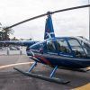 Un elegante helicóptero azul en el helipuerto, enmarcado por palmeras y un barco distante, inspira sueños de un emocionante "Vuelo en helicóptero sobre el Cañón Tajo de los Vados", que ofrece impresionantes vistas. - ForTwo - Planes para parejas