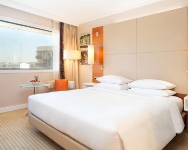 Alójese en el Hotel Hilton de Barcelona y disfrute de una experiencia moderna con una cama grande, elegantes mesitas de noche y una mesa redonda con una planta. Disfrute de las vibrantes vistas de la ciudad desde su ventana, capturando la esencia de este icónico destino. - ForTwo - Planes para parejas