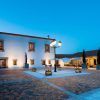 El patio de Escapada Hospes Palacio de Arenales, con sus paredes blancas y sus brillantes farolas, ofrece mesas cubiertas por sombrillas que evocan el ambiente sereno de un encantador desayuno. - ForTwo - Planes para parejas