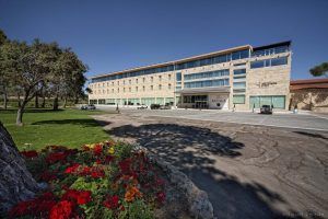 La "Habitación mágica en el Hotel Spa Arzuaga (Valladolid)" cuenta con una fachada de piedra y coches aparcados frente a un exuberante césped con flores vibrantes, mezclando elegancia y naturaleza a la perfección para darle un toque de magia vallisoletana. - ForTwo - Planes para parejas