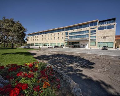 La "Habitación mágica en el Hotel Spa Arzuaga (Valladolid)" cuenta con una fachada de piedra y coches aparcados frente a un exuberante césped con flores vibrantes, mezclando elegancia y naturaleza a la perfección para darle un toque de magia vallisoletana. - ForTwo - Planes para parejas
