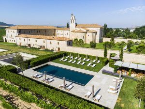 Vista aérea de la Estancia en la Abadía Retuerta LeDomaine (Valladolid), que muestra una villa con piscina, tumbonas y exuberantes jardines con un telón de fondo montañoso. - ForTwo - Planes para parejas