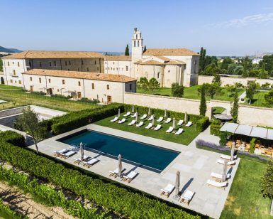 Vista aérea de la Estancia en la Abadía Retuerta LeDomaine (Valladolid), que muestra una villa con piscina, tumbonas y exuberantes jardines con un telón de fondo montañoso. - ForTwo - Planes para parejas