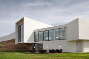 Ubicado en Logroño, el moderno y blanco Hotel-Bodega Finca de Los Arandinos cuenta con amplios ventanales y un acogedor patio con sillas y mesas con vistas a un exuberante césped bajo un cielo nublado, ofreciendo una escapada tranquila donde la comodidad se encuentra con la naturaleza. - ForTwo - Planes para parejas