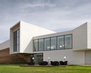 Ubicado en Logroño, el moderno y blanco Hotel-Bodega Finca de Los Arandinos cuenta con amplios ventanales y un acogedor patio con sillas y mesas con vistas a un exuberante césped bajo un cielo nublado, ofreciendo una escapada tranquila donde la comodidad se encuentra con la naturaleza. - ForTwo - Planes para parejas