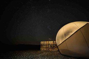 Bajo el cielo estrellado, la estructura de cúpula y el marco de madera sobre suelo de guijarros del Hotel Aire de Bardenas evocan una serena escena de base lunar. - ForTwo - Planes para parejas