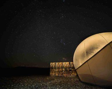 Bajo el cielo estrellado, la estructura de cúpula y el marco de madera sobre suelo de guijarros del Hotel Aire de Bardenas evocan una serena escena de base lunar. - ForTwo - Planes para parejas