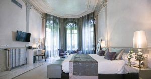 Descubra una estancia refinada en Hospes Palacio de los Patos con una elegante habitación con una cama grande, decoración moderna, TV, escritorio y zona de estar junto a ventanales. Eleva tu experiencia con "Disfruta de un fin de semana de lujo con spa en Hospes Palacio de los Patos (Granada). - ForTwo - Planes para parejas