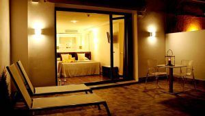Relájese en una acogedora habitación de hotel con cama doble, con vistas a un patio con tumbonas y una mesa pequeña. Disfrute de la cálida iluminación mientras saborea un cóctel después de disfrutar de la Escapada con piscina, cóctel y visita guiada (Sevilla). - ForTwo - Planes para parejas