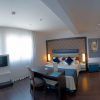 Habitación en el Hotel Gran Versalles Madrid con cama de matrimonio, escritorio, TV y grandes ventanales con cortinas transparentes. - ForTwo - Planes para parejas