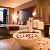 Habitación de lujo en el Hotel Miramar Barcelona GL, con bañera adornada con pétalos de rosa, cama de felpa y una impresionante vista al mar al atardecer. - ForTwo - Planes para parejas