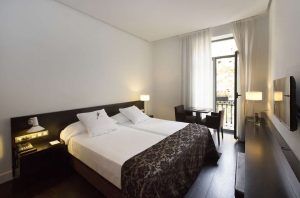 Disfrute de una estancia en Escapada Hospes Palau de la Mar en Valencia, con una moderna habitación con dos camas, zona de estar, lámparas, TV y una ventana con cortinas transparentes. Empiece el día con un desayuno y disfrute de las lujosas ofertas del spa. - ForTwo - Planes para parejas