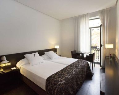 Disfrute de una estancia en Escapada Hospes Palau de la Mar en Valencia, con una moderna habitación con dos camas, zona de estar, lámparas, TV y una ventana con cortinas transparentes. Empiece el día con un desayuno y disfrute de las lujosas ofertas del spa. - ForTwo - Planes para parejas