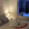 Experimente la Escapada Romántica en Suite con Jacuzzi en el Hotel Adealba, Mérida, con toallas de cisne adornando la cama y un rastro de pétalos de rosa que conduce a su bañera de hidromasaje privada iluminada en la esquina. - ForTwo - Planes para parejas
