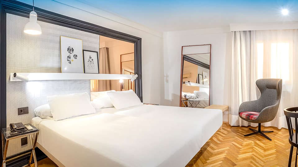 Descubra Escapada SH Inglés Boutique + desayuno en Valencia: un refugio contemporáneo con una cama grande, obras de arte cautivadoras y un cómodo sillón. La brillante iluminación realza el hermoso suelo con motivos de madera, ofreciendo el refugio ideal para una escapada perfecta. - ForTwo - Planes para parejas