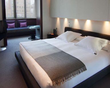 Descubra la elegancia moderna del Escapada Hotel SixtyTwo en Barcelona, con una cama espaciosa, iluminación de acento y una acogedora zona de estar junto a la ventana con impresionantes vistas a la ciudad. Además, disfrute de un cava con brochetas de fruta mientras se relaja con su programa favorito en este elegante santuario. - ForTwo - Planes para parejas