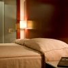 Relájese en una cama doble en el Escapada Hotel Zenit de Valencia, con paredes de madera y una cálida lámpara de pared. Disfrute del casco histórico, saboree una paella y acceda a la sauna y al gimnasio. - ForTwo - Planes para parejas