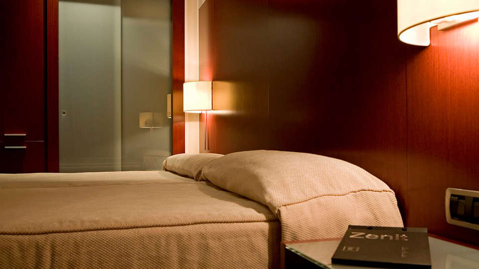 Relájese en una cama doble en el Escapada Hotel Zenit de Valencia, con paredes de madera y una cálida lámpara de pared. Disfrute del casco histórico, saboree una paella y acceda a la sauna y al gimnasio. - ForTwo - Planes para parejas