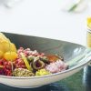 En el romántico Restaurante Ibiza Hoyo 19 se sirve un plato gourmet con tartar, patatas fritas, alcaparras y cebollas elegantemente presentadas con patatas fritas en una cesta de alambre. - ForTwo - Planes para parejas