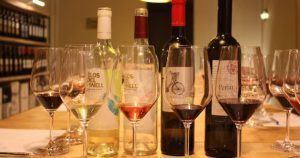 Las muestras de Cata de vinos en Barcelona se presentan elegantemente dispuestas con botellas de vino y copas sobre una mesa en una bodega cerca de las encantadoras calles de Barcelona. - ForTwo - Planes para parejas