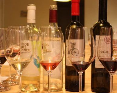 Las muestras de Cata de vinos en Barcelona se presentan elegantemente dispuestas con botellas de vino y copas sobre una mesa en una bodega cerca de las encantadoras calles de Barcelona. - ForTwo - Planes para parejas